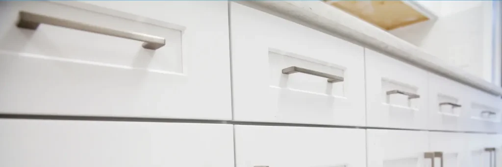 Close-up of white kitchen cabinets with silver handles and a light-colored countertop